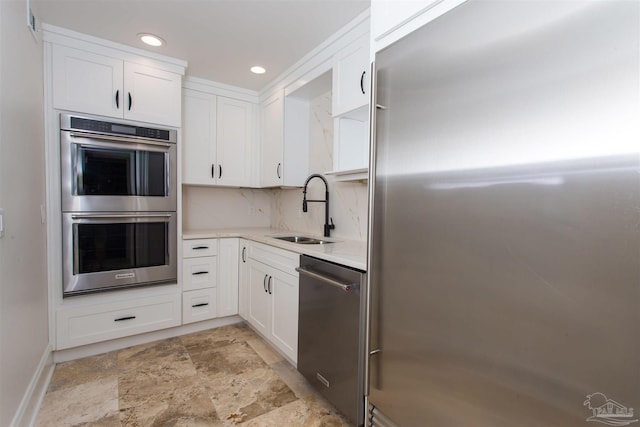 kitchen with decorative backsplash, white cabinetry, stainless steel appliances, and sink