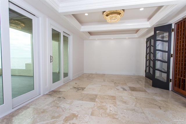 hall with a tray ceiling, ornamental molding, and an inviting chandelier