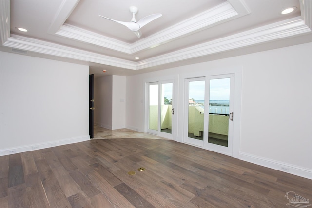 empty room featuring ceiling fan, a raised ceiling, ornamental molding, and dark hardwood / wood-style floors