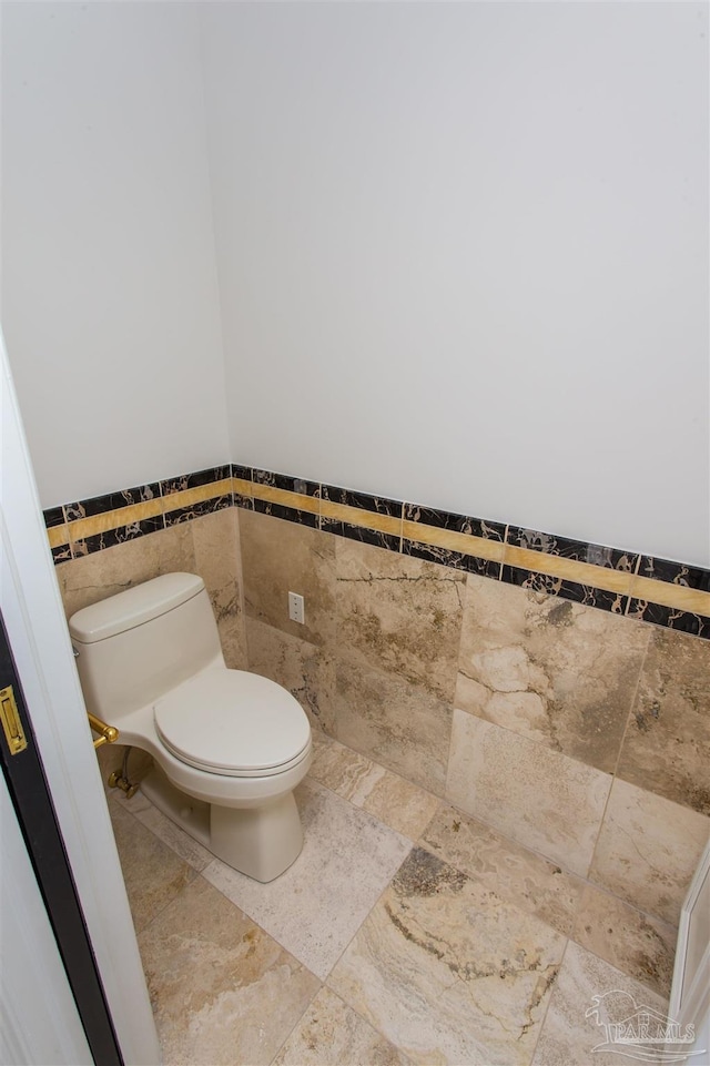 bathroom with toilet and tile walls