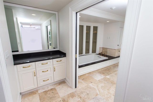 bathroom with vanity, ornamental molding, and a tub