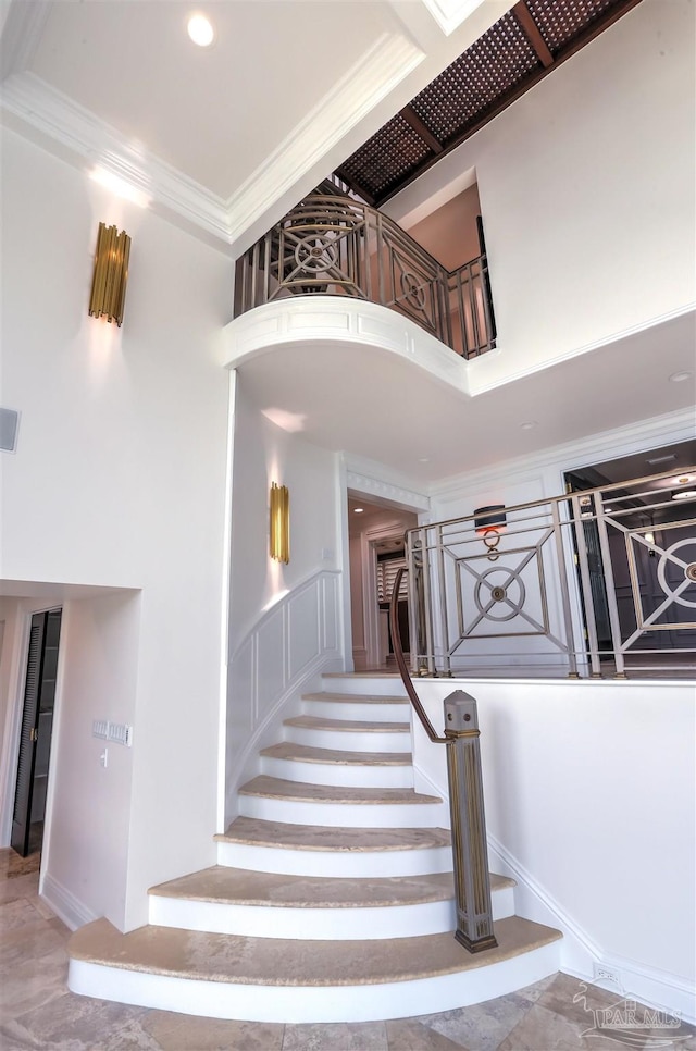 stairs featuring ornamental molding and a high ceiling