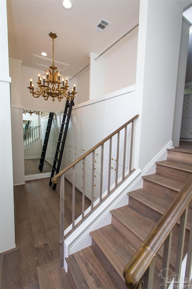 stairway featuring hardwood / wood-style floors and a chandelier