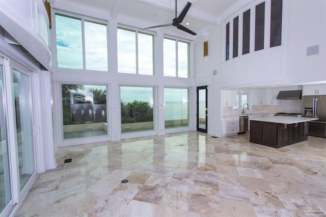 unfurnished living room featuring beam ceiling, ornamental molding, a high ceiling, and ceiling fan