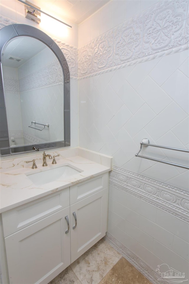 bathroom featuring vanity and tile walls