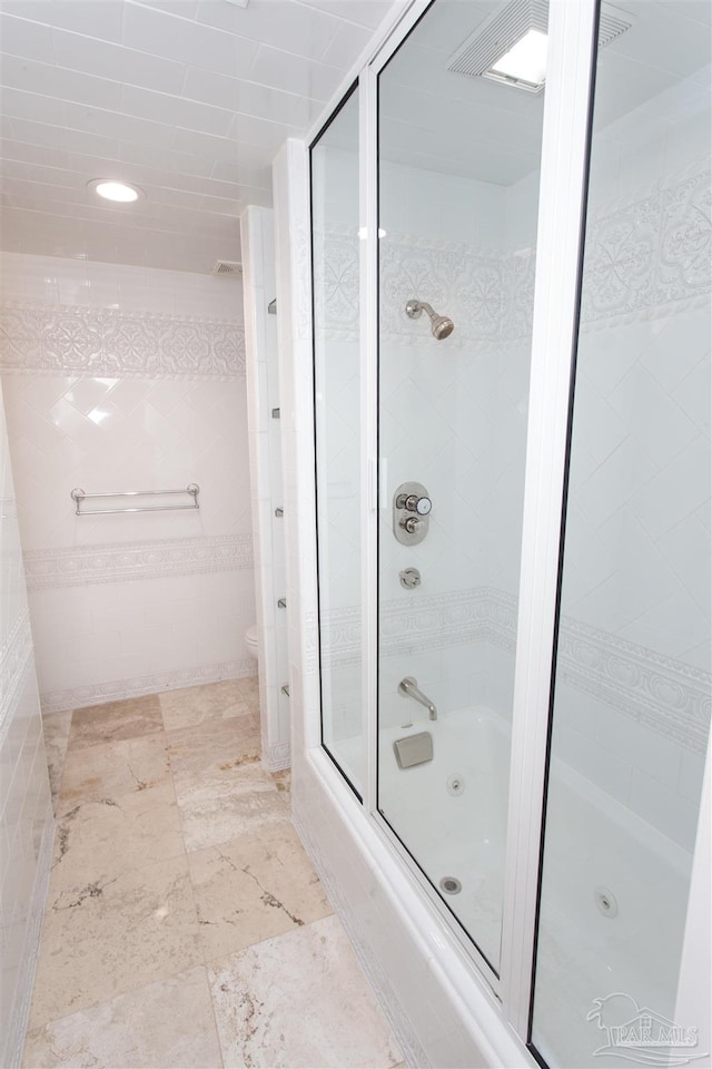 bathroom with bath / shower combo with glass door and toilet