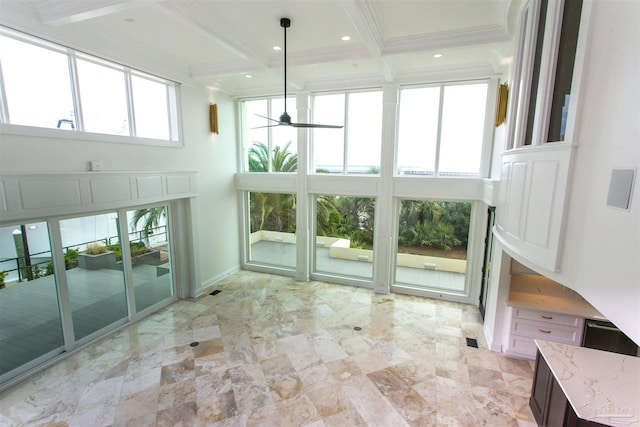 unfurnished sunroom with beam ceiling, a healthy amount of sunlight, and ceiling fan