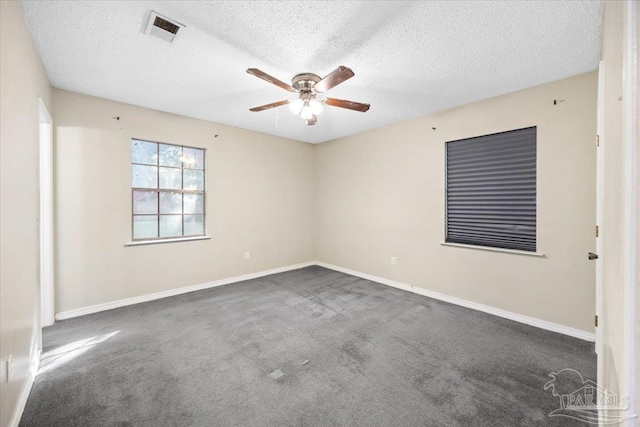 spare room featuring dark colored carpet and a textured ceiling