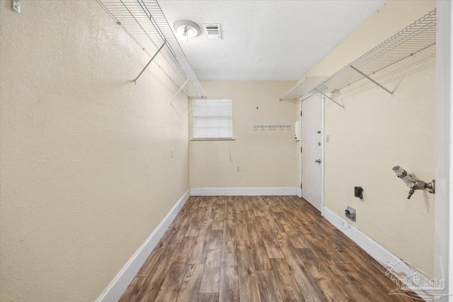 interior space featuring electric dryer hookup, a textured ceiling, and hardwood / wood-style flooring