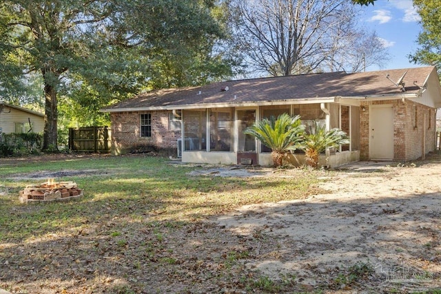 back of property featuring a fire pit and a sunroom