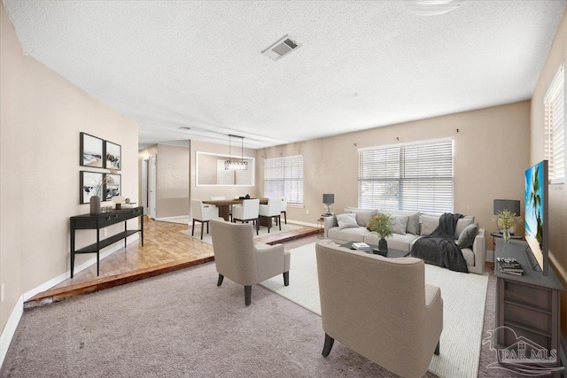 living room with a textured ceiling, light carpet, and a chandelier