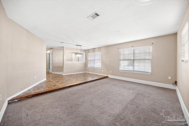 spare room featuring carpet flooring and a textured ceiling