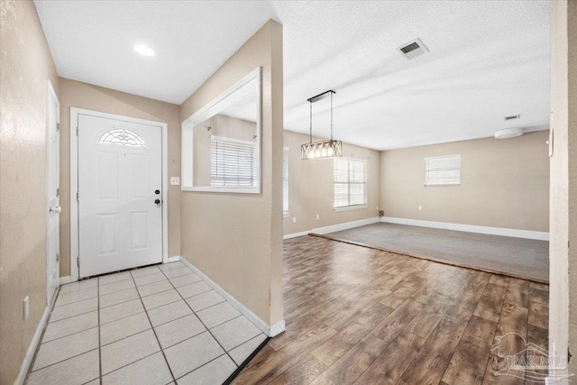 foyer featuring hardwood / wood-style floors, a textured ceiling, and a chandelier