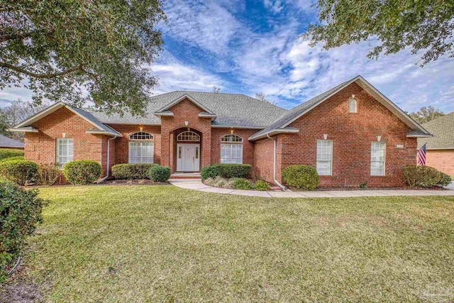 traditional home featuring brick siding, a shingled roof, and a front lawn