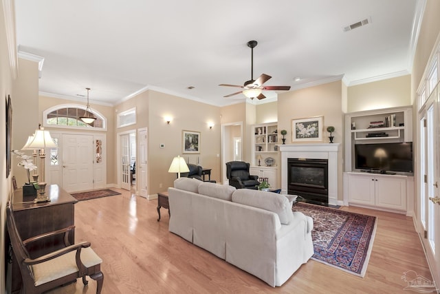 living area with visible vents, baseboards, light wood-style floors, and a glass covered fireplace