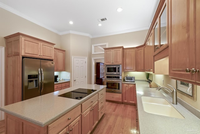 kitchen featuring visible vents, a sink, appliances with stainless steel finishes, crown molding, and light countertops