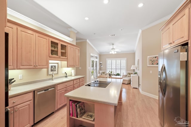 kitchen featuring light brown cabinets, a sink, appliances with stainless steel finishes, crown molding, and a center island