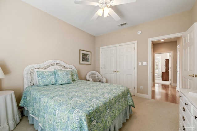 bedroom with visible vents, baseboards, light colored carpet, a closet, and a ceiling fan