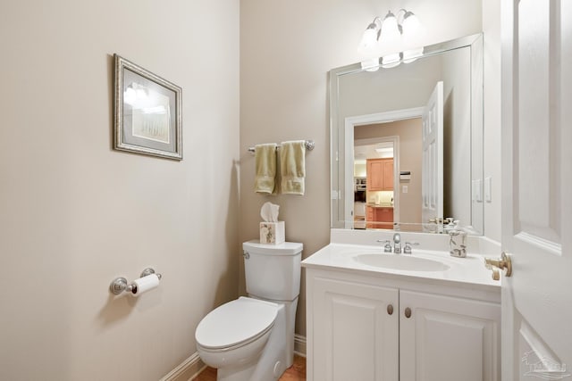 half bath featuring vanity, toilet, and baseboards