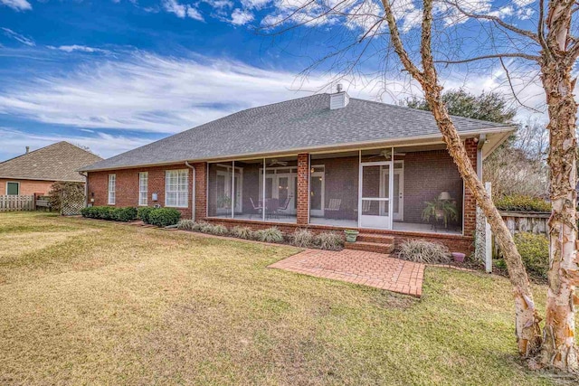 back of property with brick siding, a lawn, and a sunroom