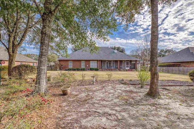 single story home with a front yard, fence, brick siding, and a sunroom