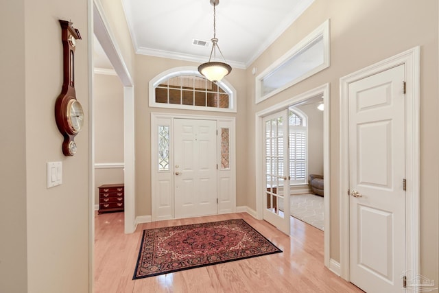 foyer featuring visible vents, wood finished floors, and crown molding