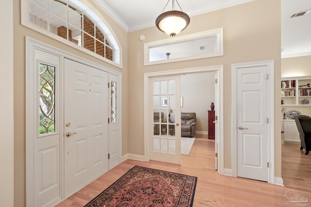 entrance foyer featuring crown molding, light wood-style flooring, baseboards, and visible vents