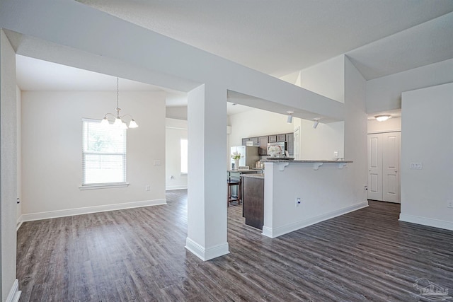 257 Millet Cir, Cantonment, FL 32533 - unfurnished living room featuring baseboards, vaulted ceiling, dark wood-style floors, and a notable chandelier