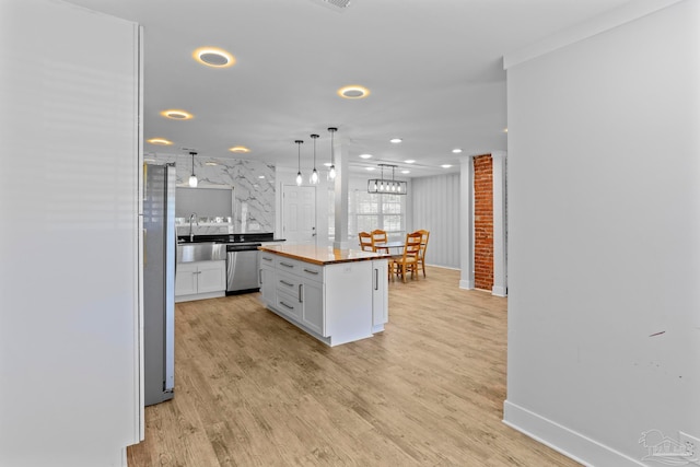 kitchen featuring white cabinetry, a center island, stainless steel appliances, light hardwood / wood-style floors, and butcher block countertops