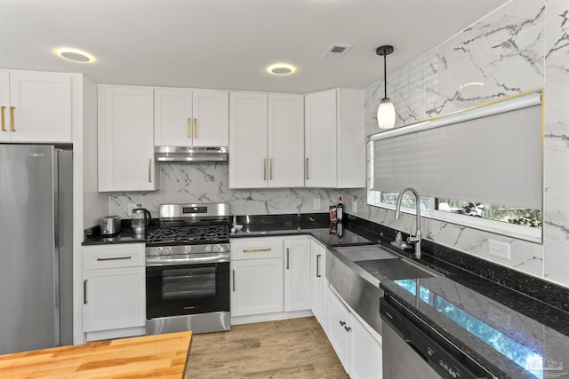 kitchen with white cabinetry, decorative light fixtures, light wood-type flooring, appliances with stainless steel finishes, and backsplash