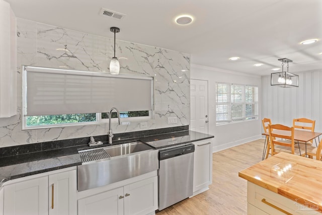 kitchen with decorative light fixtures, stainless steel dishwasher, dark stone countertops, and light hardwood / wood-style flooring