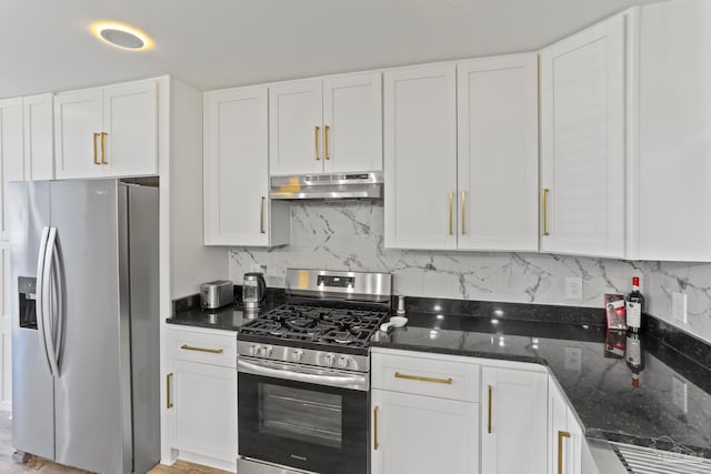 kitchen featuring appliances with stainless steel finishes, white cabinetry, dark stone countertops, and backsplash