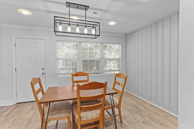 dining area featuring an inviting chandelier, crown molding, and light hardwood / wood-style flooring