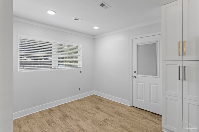 spare room featuring crown molding and light wood-type flooring