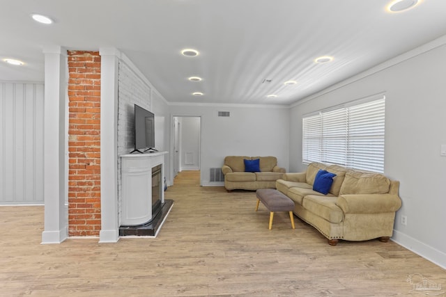 living room featuring light hardwood / wood-style floors, brick wall, and crown molding