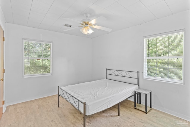 bedroom with multiple windows, light hardwood / wood-style flooring, and ceiling fan