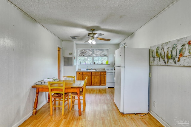 dining room with a textured ceiling, light hardwood / wood-style flooring, sink, and ceiling fan