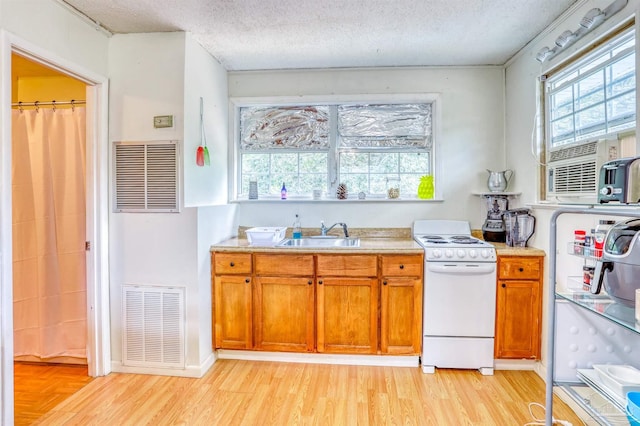 kitchen with plenty of natural light, sink, white gas stove, and a textured ceiling