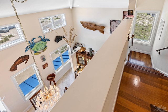 stairs featuring plenty of natural light, wood-type flooring, and vaulted ceiling