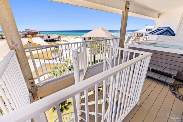 wooden terrace with a beach view, a water view, and a hot tub