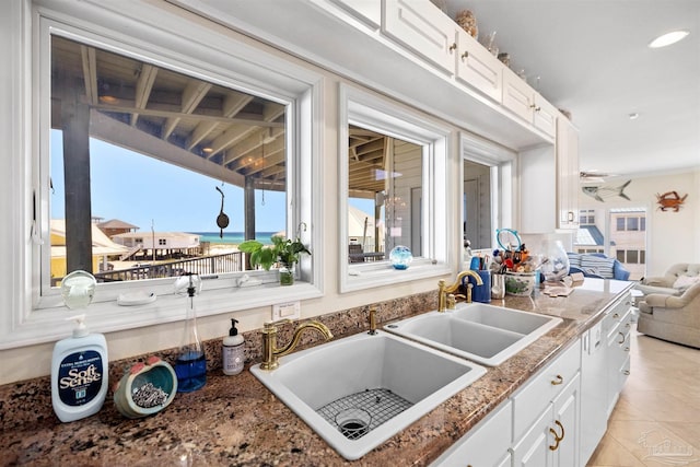 kitchen with white cabinets, plenty of natural light, light tile patterned flooring, and sink