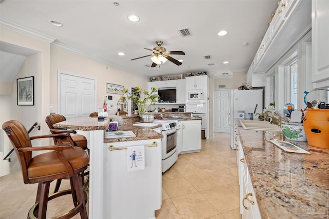 kitchen featuring white cabinetry, ceiling fan, white appliances, a breakfast bar area, and a kitchen island