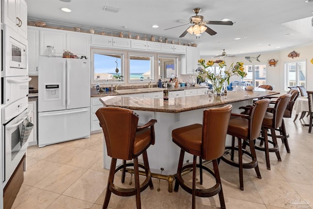 kitchen with white cabinets, white appliances, a center island, and ceiling fan