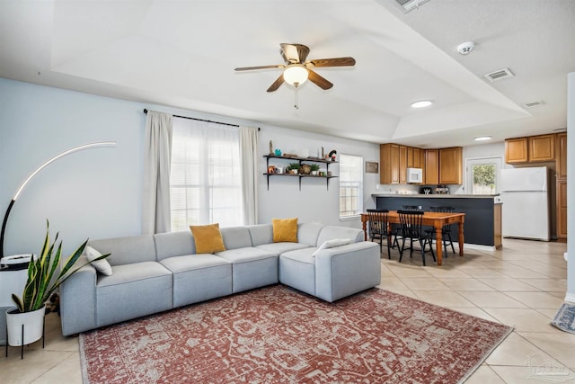 tiled living room featuring a raised ceiling and ceiling fan