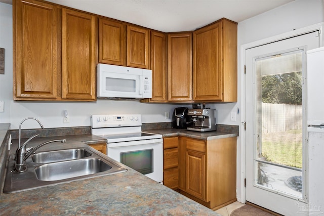 kitchen featuring white appliances, sink, and light tile patterned floors