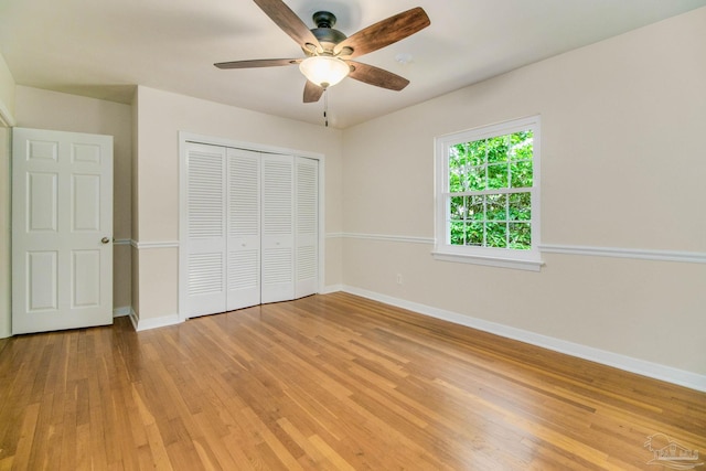 unfurnished bedroom with ceiling fan, light wood-type flooring, and a closet