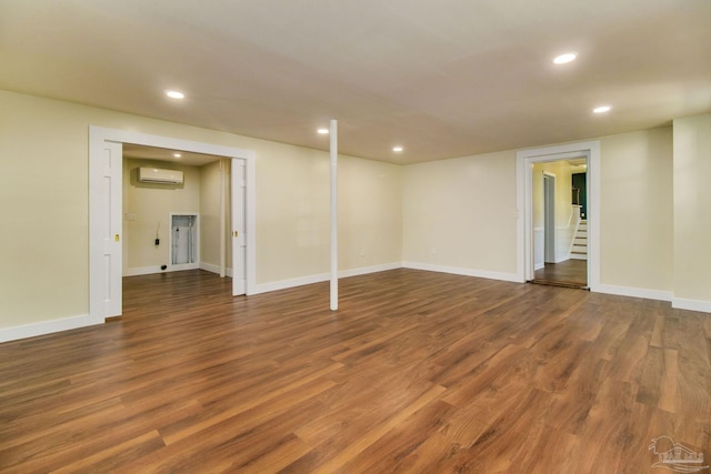 basement with dark wood-type flooring and a wall mounted AC