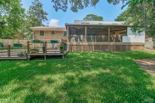 back of property featuring a lawn, a sunroom, and a deck