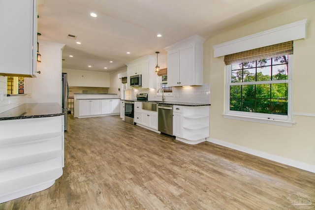 kitchen with pendant lighting, appliances with stainless steel finishes, light wood-type flooring, and white cabinets