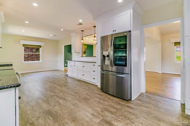 kitchen with stainless steel refrigerator with ice dispenser, white cabinetry, dark stone countertops, light hardwood / wood-style floors, and backsplash